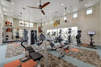 Fitness center with excercise bikes, ellipticals, ceiling fan and patterned rug